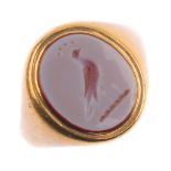 A gem-set signet ring. The oval carnelian, carved to depict bird and foliate motif, with tapered