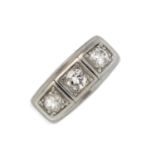 A diamond three-stone ring. The brilliant-cut diamond line, within a raised rectangular panel and