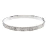 An 18ct gold diamond hinged bangle. With pave-set diamond sides. One diamond deficient. Estimated