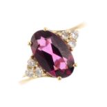 A 9ct gold garnet and diamond dress ring. The oval-shape garnet, with single-cut diamond trefoil