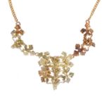 A 9ct gold necklace, designed as a bi-colour grape and vine motif panel, with similarly-designed