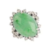 A jade and diamond cluster ring. The oval jadeite cabochon, with brilliant-cut diamond surround