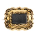 A late Victorian memorial brooch. The rectangular-shape glazed panel, with scrolling surrounds.