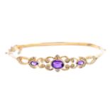 A 9ct gold amethyst and diamond hinged bangle. Of openwork design, the oval and pear-shape