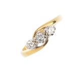 An 18ct gold diamond three-stone ring. Designed as a brilliant-cut diamond off-set line, with