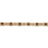 A 9ct gold garnet bracelet. Designed as a series of oval-shape garnets, each with bar sides and