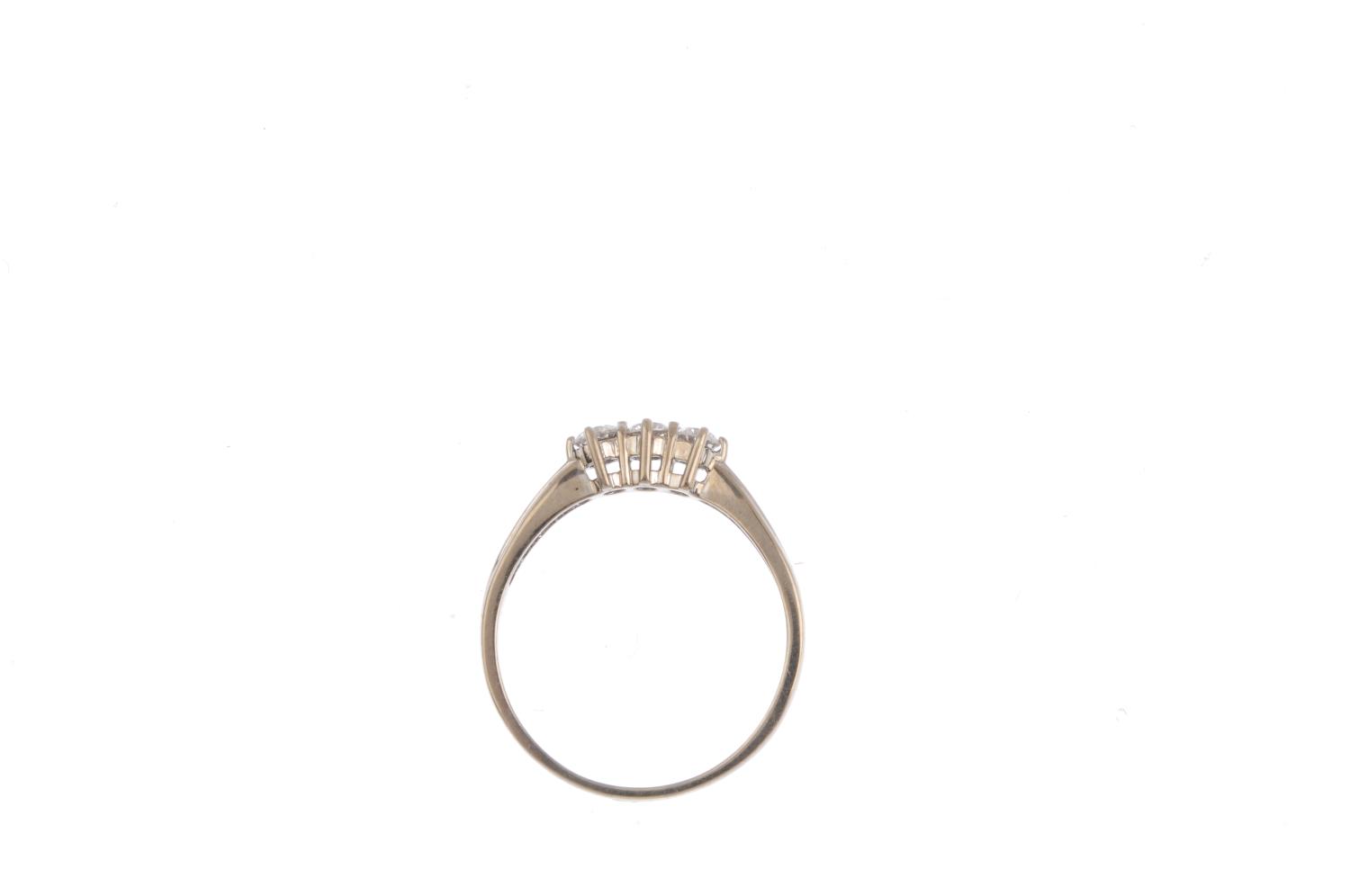 An 18ct gold diamond three-stone ring. The brilliant-cut diamond line, with grooved shoulders and - Image 2 of 3