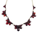 A garnet necklace. Designed as a series of graduated oval-shape garnet cluster panels, suspended