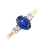 An 18ct gold sapphire and diamond three-stone ring. The oval-shape sapphire, with brilliant-cut