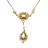 An early 20th century gold peridot necklace. The pear-shape peridot suspended from a cushion-shape