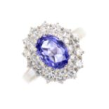 An 18ct gold tanzanite and diamond cluster ring. The oval-shape tanzanite, with brilliant-cut
