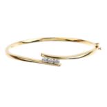 An 18ct gold diamond hinged bangle. The brilliant-cut diamond line, with crossover sides.