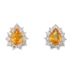 A pair of sapphire and diamond cluster earrings. Each designed as a pear-shape yellow sapphire, with