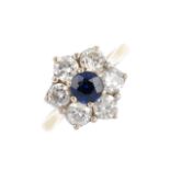 An 18ct gold sapphire and diamond cluster ring. The circular-shape sapphire, with brilliant-cut