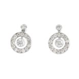 A pair of diamond earrings. Each designed as a brilliant-cut diamond collet, suspended within a