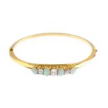 An early 20th century 15ct gold opal and diamond hinged bangle. The alternating oval opal cabochon