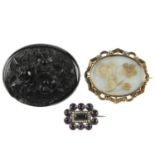 Three late Victorian brooches. To include an oval jet brooch with carved floral decoration, a