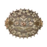 A late Victorian silver brooch. Of oval outline, with applied vari-colour leaves to the border and