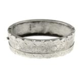 A late Victorian silver hinged bangle. Designed with engraved floral and foliate decoration to the