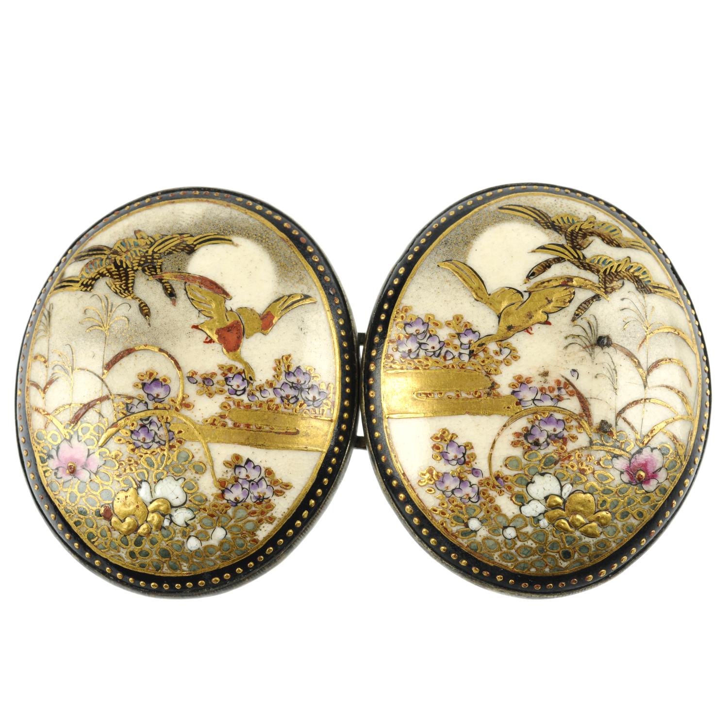 A Satsuma buckle. Designed as two oval panels painted to depict birds in flight above flower beds,