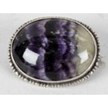 A Blue John brooch. The oval cabochon, possibly Millers vein, within white metal surround with
