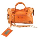 BALENCIAGA - an orange Classic City handbag. Crafted from distressed orange lambskin leather,