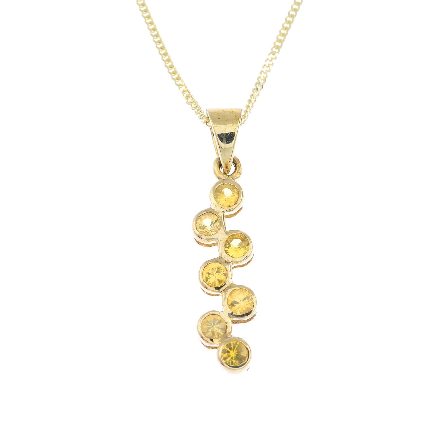 A 9ct gold sapphire pendant. The yellow sapphire scrolling line, with tapered surmount, suspended