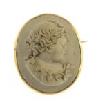 A mid Victorian gold lava cameo brooch. The oval lava cameo, carved to depict a young child with