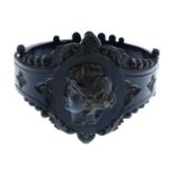 A late Victorian jet bangle. Designed as a carved panel depicting a face in profile, applied to an
