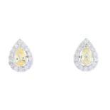 A pair of sapphire and diamond earrings. Each designed as a pear-shape yellow sapphire, with