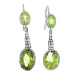 A pair of peridot and diamond earrings. Each designed as an oval-shape peridot collet, suspended