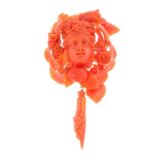 A mid 19th century coral brooch. Carved to depict a bacchante, with floral and foliate surrounds,