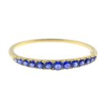 An early 20th century 18ct gold, sapphire and diamond bangle. Designed as a graduated circular-shape