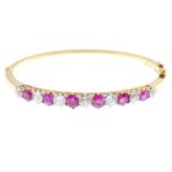 An Edwardian 18ct gold Burmese ruby and diamond bangle. Designed as an alternating cushion-shape