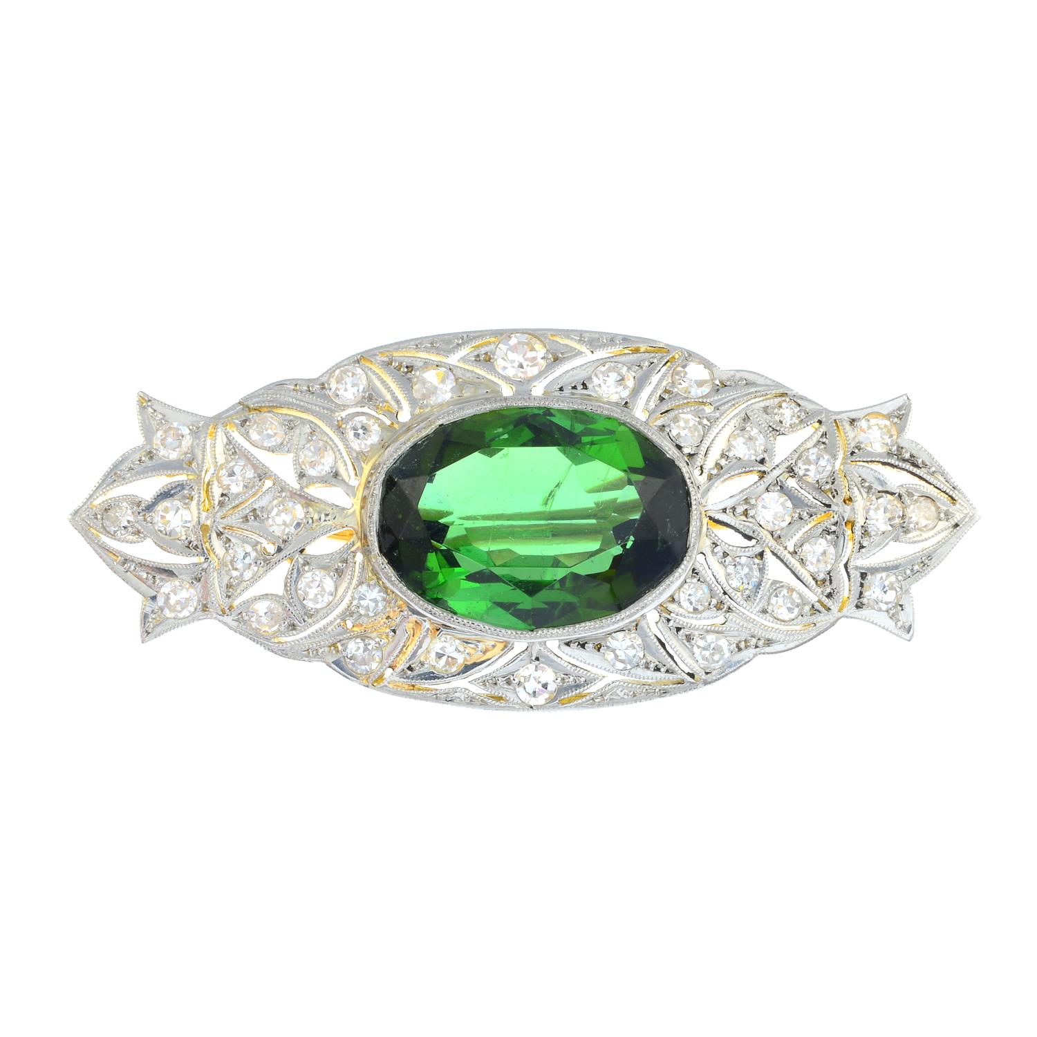 A tourmaline and diamond brooch. Of openwork design, the oval-shape green tourmaline, with