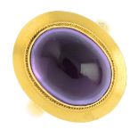 An early 20th century 9ct gold amethyst ring. The oval amethyst cabochon, with rope-twist surround