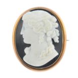 An early 20th century gold onyx brooch. Of oval outline, the agate carved to depict a lady in