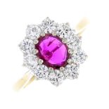 An 18ct gold ruby and diamond cluster ring. The oval-shape ruby, with brilliant-cut diamond