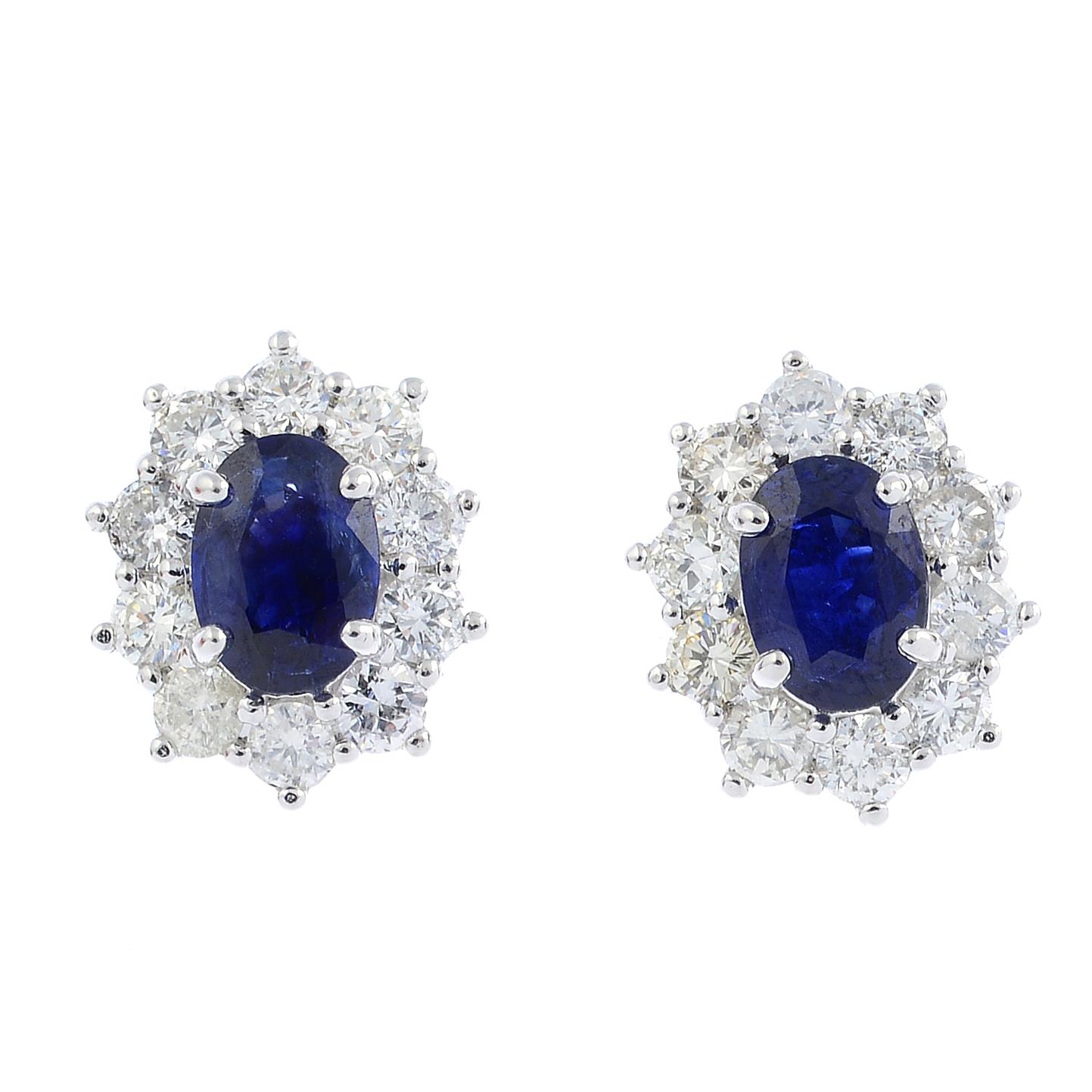 A pair of sapphire and diamond cluster earrings. Each designed as an oval-shape sapphire, with