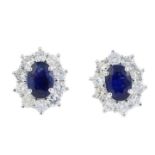 A pair of sapphire and diamond cluster earrings. Each designed as an oval-shape sapphire, with