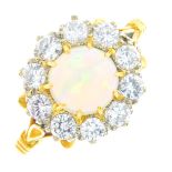 An 18ct gold opal and diamond cluster ring. The circular opal cabochon, with brilliant-cut diamond