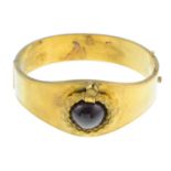 A late 19th century suite of jewellery. The hinged bangle with garnet cabochon and wreath motif,