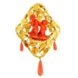 A mid Victorian gold coral brooch. The coral carved to depict Bacchus putting his hand to Cupid's