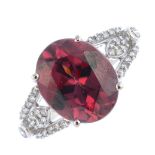 An 18ct gold zircon and diamond dress ring. The oval-shape purplish-red zircon, with brilliant-cut