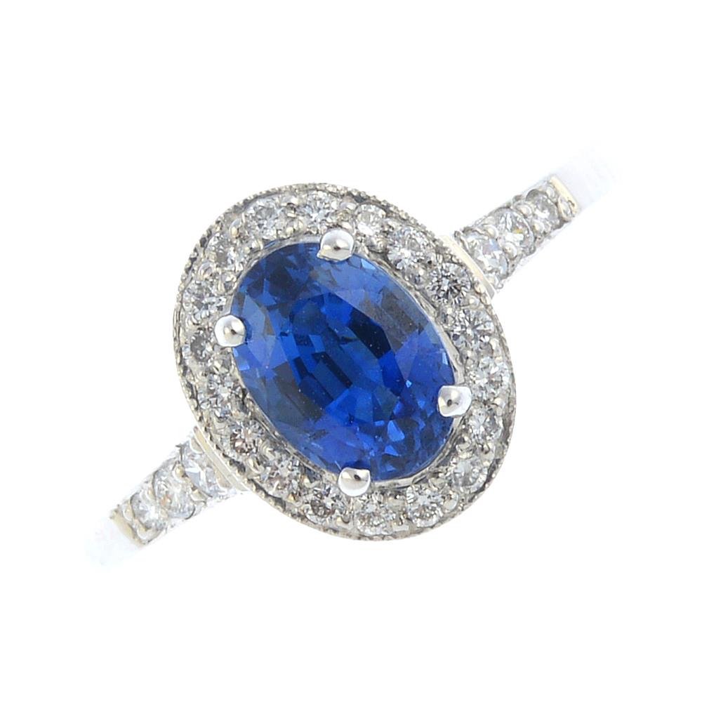 An 18ct gold sapphire and diamond cluster ring. The oval-shape sapphire, within a brilliant-cut