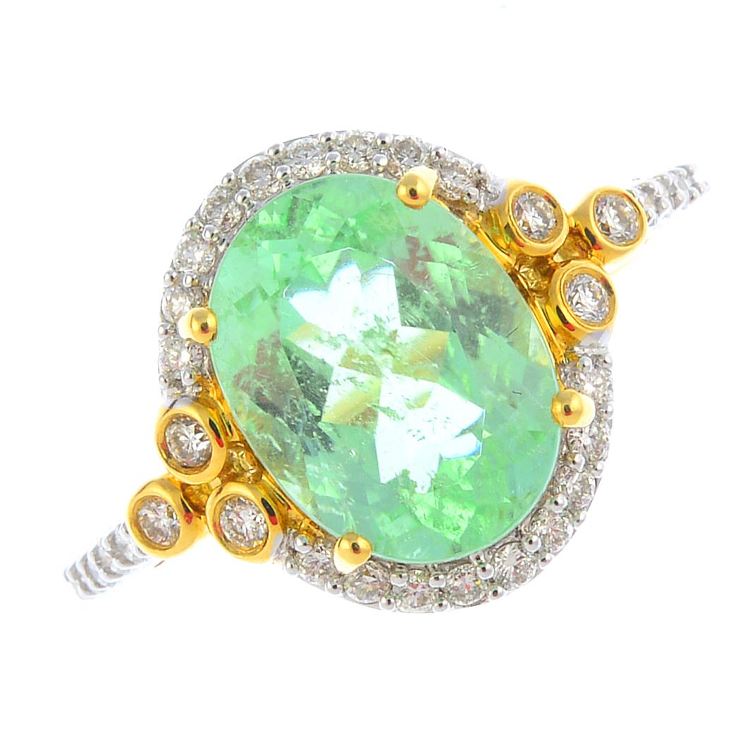 An 18ct gold tourmaline and diamond cluster ring. The oval-shape tourmaline, with brilliant-cut