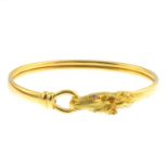 An 18ct gold ruby horse head bangle. Designed as a plain bangle, with textured horse head clasp