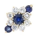 A 9ct gold sapphire and diamond cluster ring. The circular-shape sapphire, within a brilliant-cut