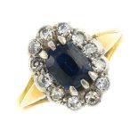 A sapphire and diamond cluster ring. The cushion-shape sapphire, within a single-cut diamond