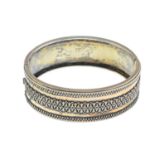 A hinged bangle and two silver bracelets. To include a geometric motif hinged bangle, a silver
